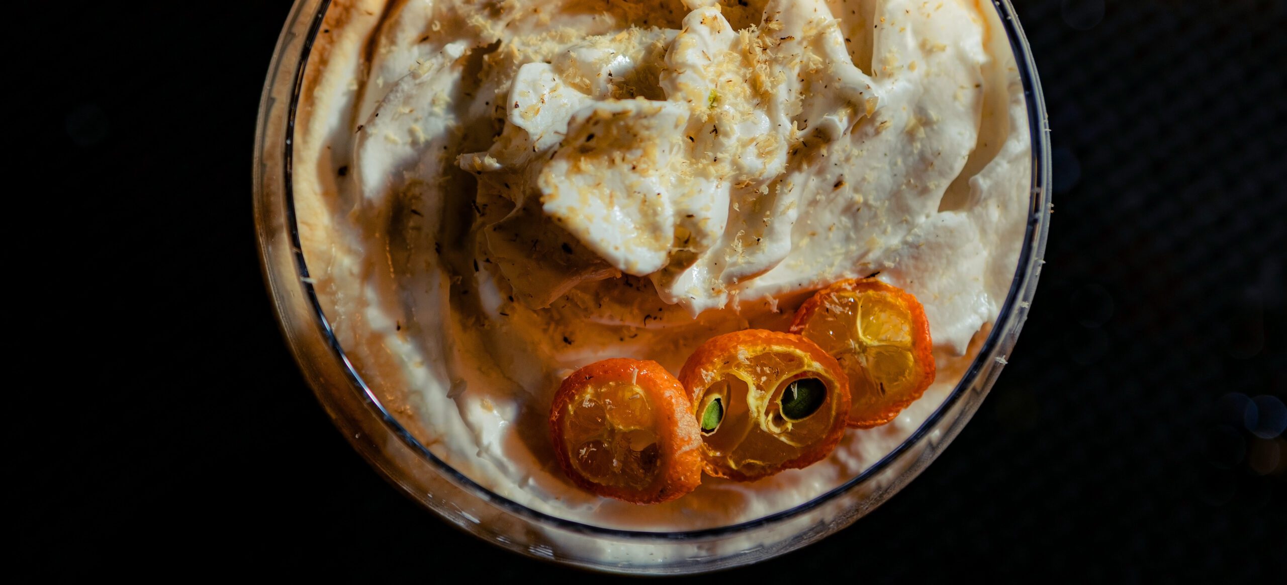 Espresso and coconut cocktail served at Palo Santo Cocktail Bar in Granollers, topped with whipped cream and candied citrus garnish.