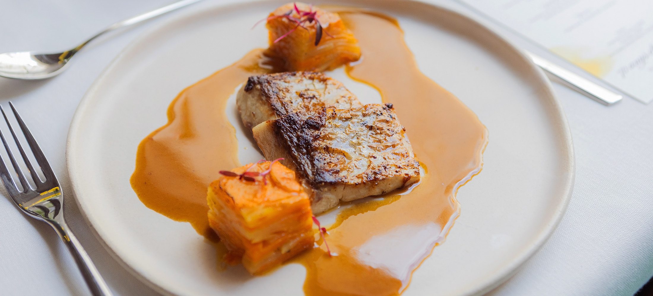 Gourmet fish course with carrot purée and rich sauce served by Esteve Catering during a private dining event in Granollers.