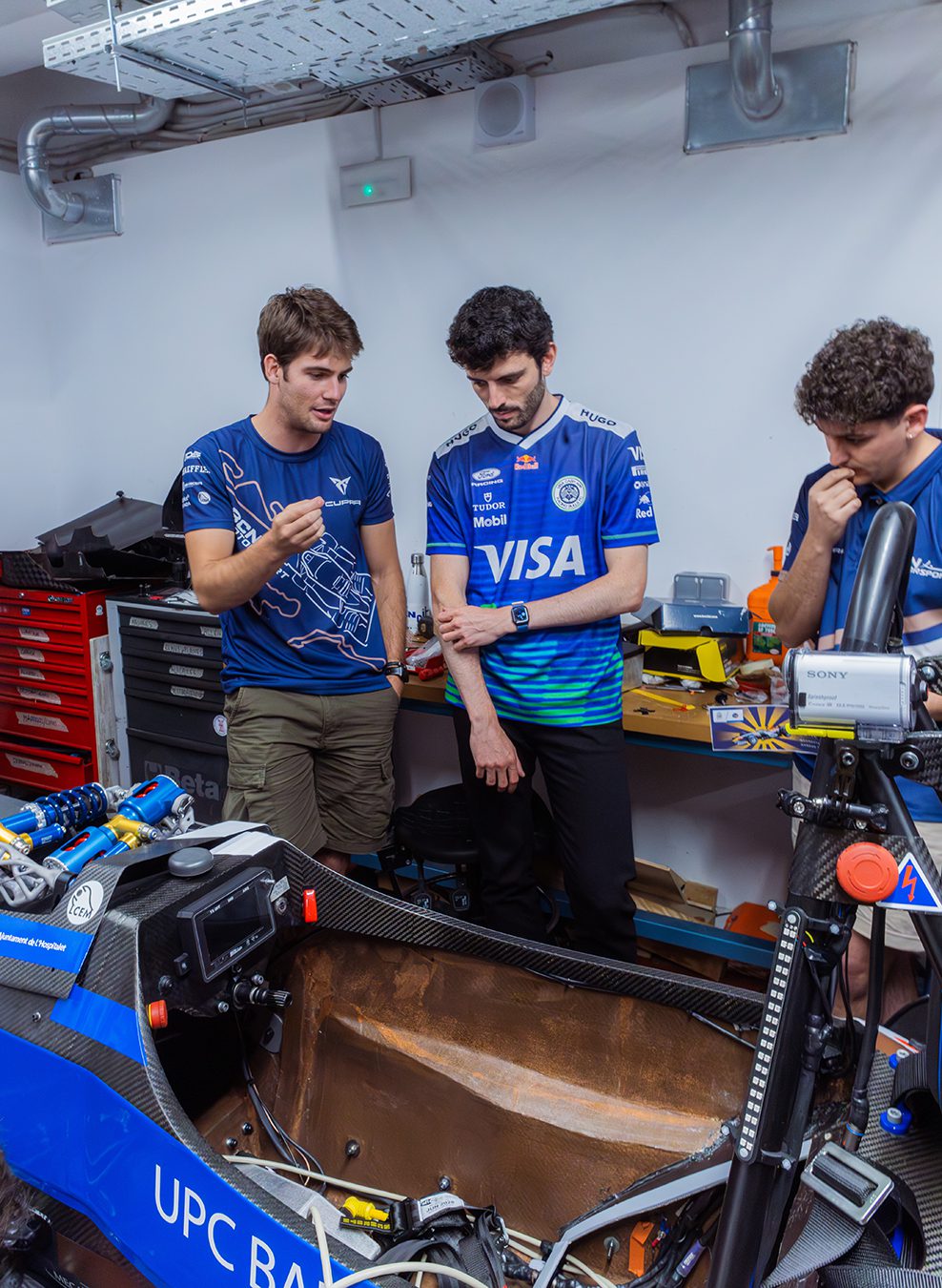 Visa Cash App Racing Bulls engineer discussing the Formula Student race car with UPC engineering students during a Formula 1 Week event in Barcelona.