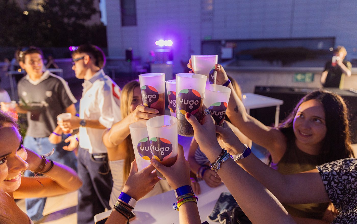 Students celebrating with Yugo-branded cups during the Final Lap Farewell rooftop party at Yugo Barcelona during Formula 1 Week, photographed by Barcelona event photographer Magdalena Bee.