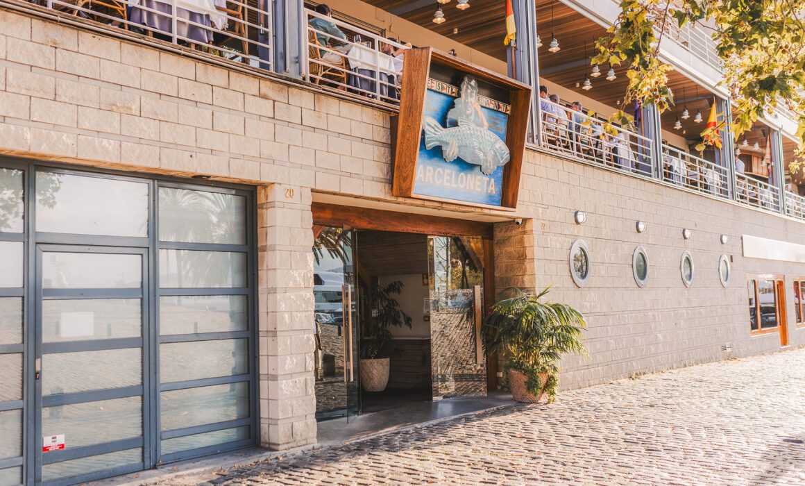 Entrance of Barceloneta Restaurant on Barcelona's waterfront with its iconic facade and marina-side location.