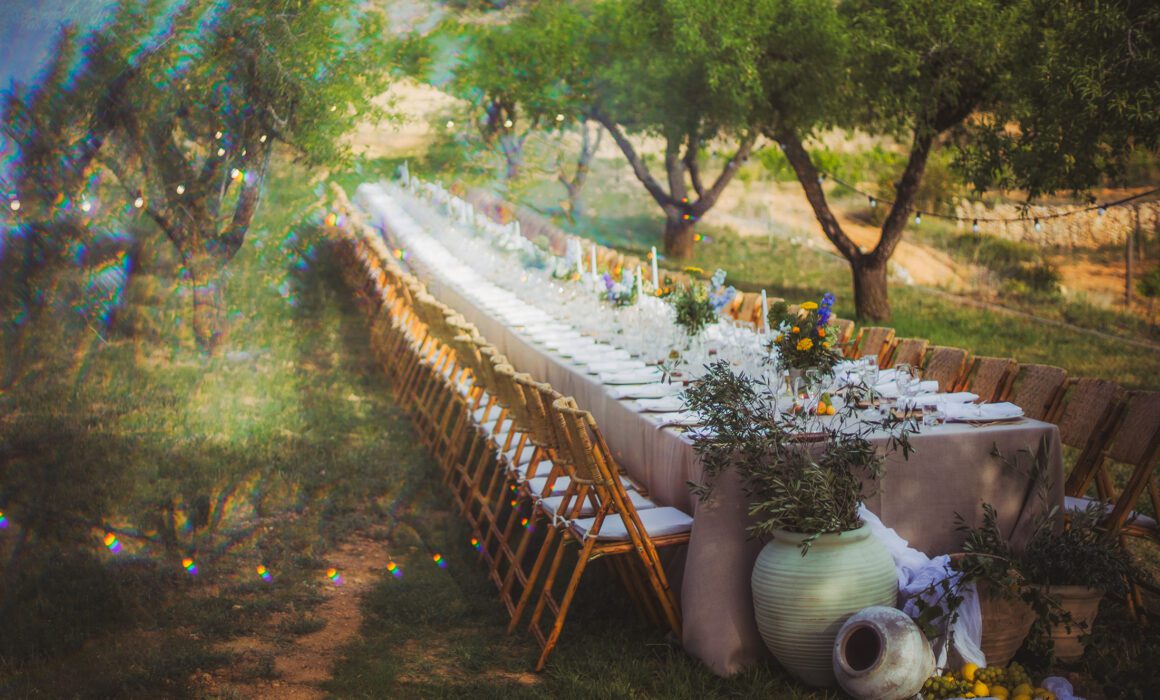 Luxury outdoor dining table set beneath Mediterranean trees at Masia Cabellut vineyard estate in Tarragona, Spain.