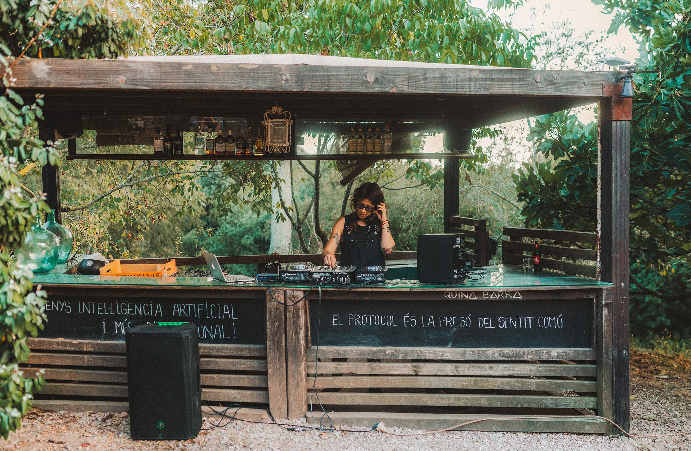 DJ performing at an outdoor wooden bar during a private event at a countryside venue near Girona, surrounded by nature at Can Pi, Girona
